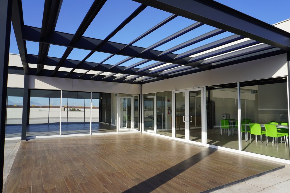 Terraza de oficinas en Monterrey con pérgola de acero y cancelería corrediza de aluminio de piso a techo