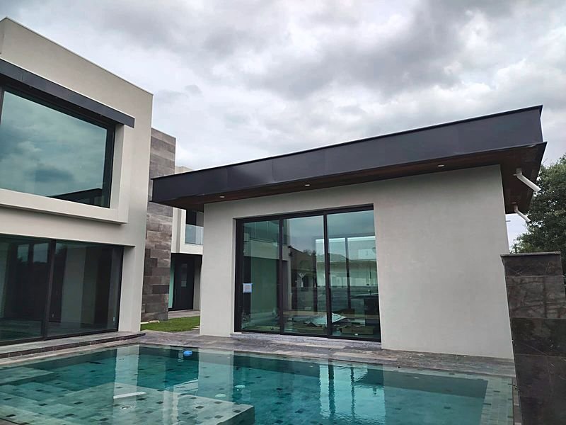 Casa contemporánea en Monterrey con corredera de tres hojas en marco negro frente a una alberca