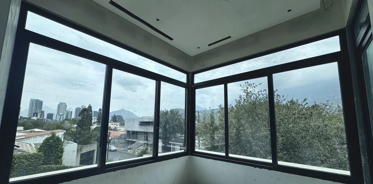 Ventana en esquina de dos paños con marco negro, con vista al skyline de San Pedro y a la sierra