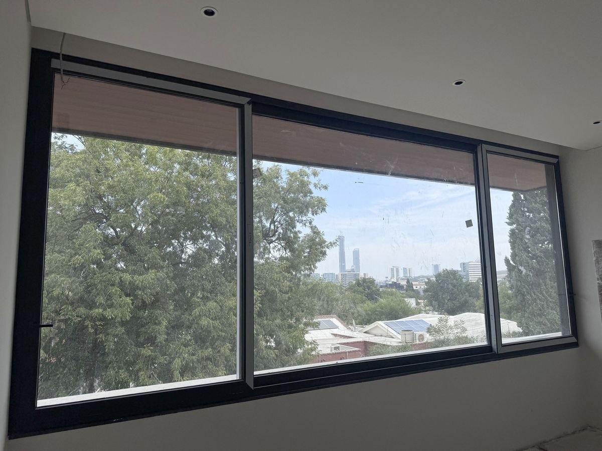 Ventanal corredizo de PVC negro en una residencia de San Pedro Garza García, con vista al skyline y al arbolado